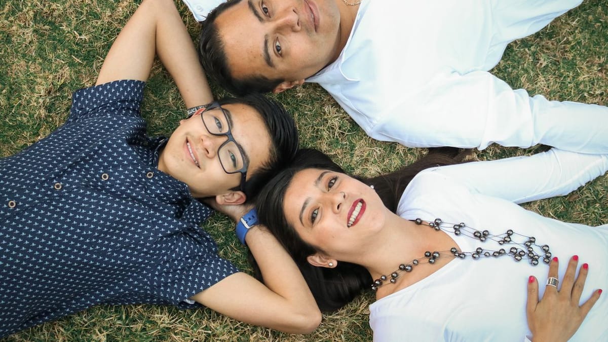 Famille complice détendue dans l'herbe avec un adolescent